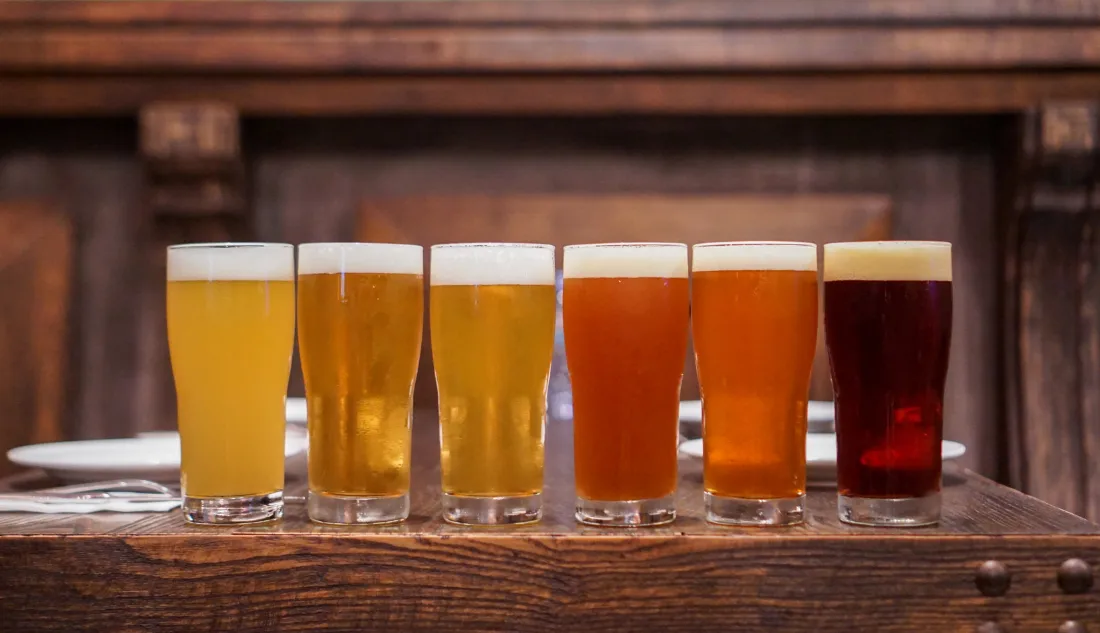 Row of craft beer glasses with different shades from pale to dark amber on a wooden bar in Branson, Missouri.