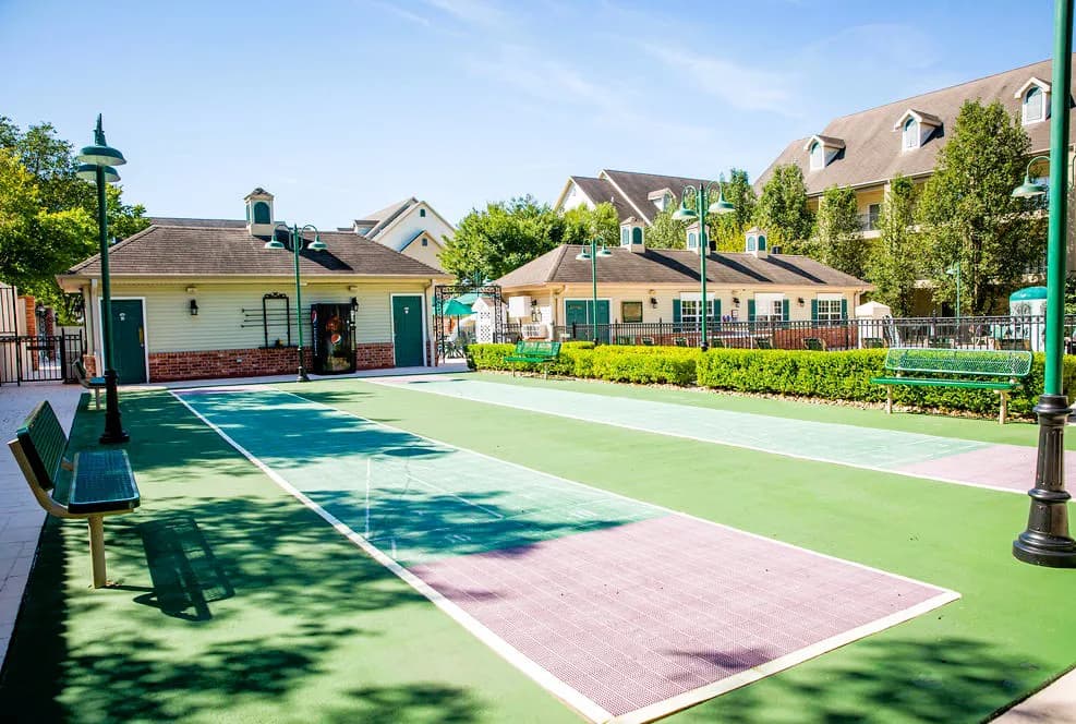 Outdoor bocce ball court with benches and surrounding greenery.